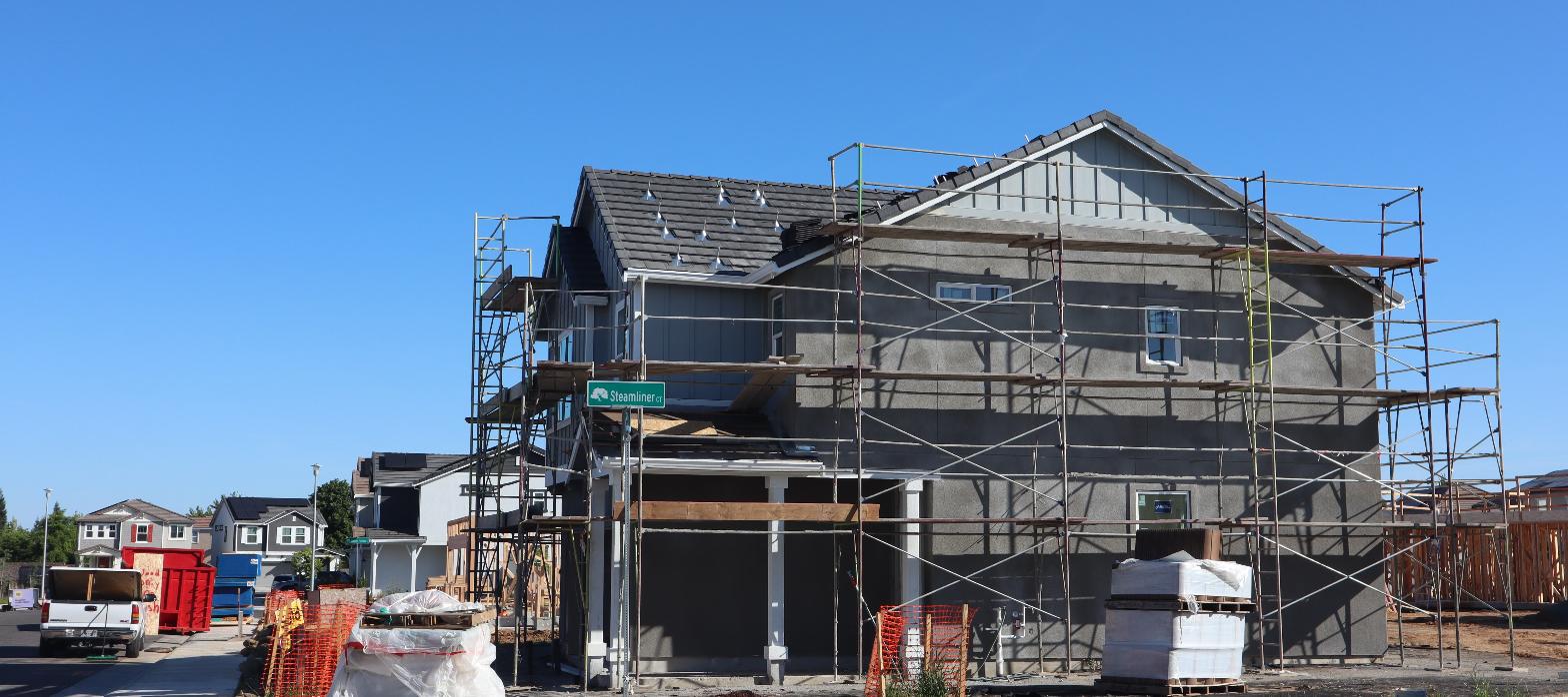 New residential construction with scaffolding on a corner lot, representing a North Philadelphia infill project.