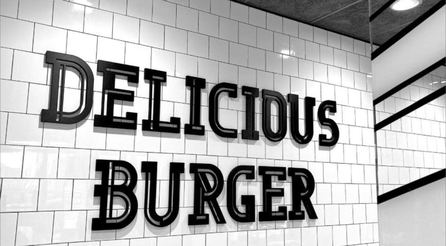 Black and white tiled restaurant wall with a burger sign, representing a second-generation smashburger buildout.