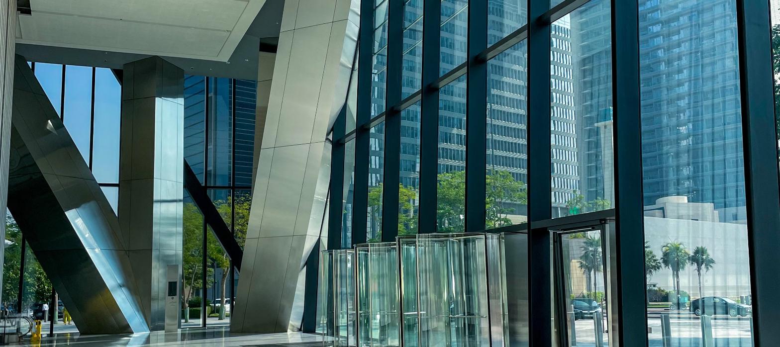 Angular glass office tower entrance with city skyline views, representing the Schuylkill Yards headquarters tower.
