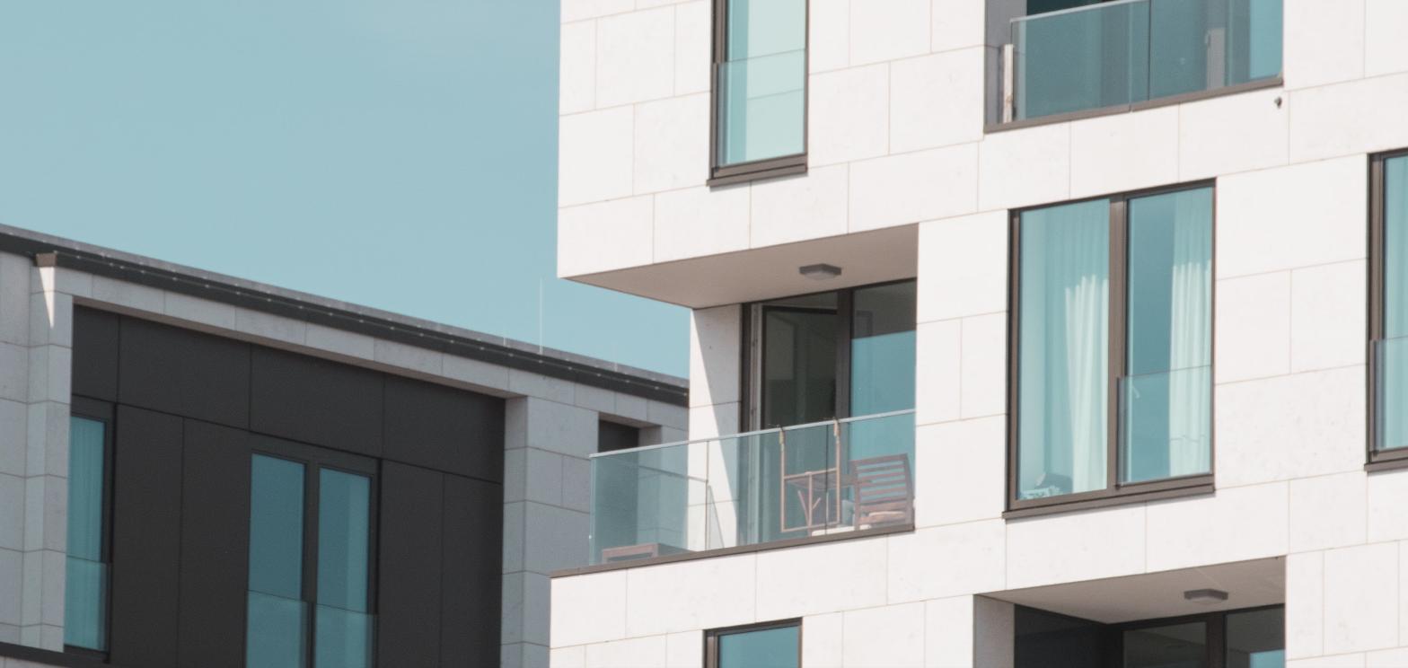 Modern apartment building facade with glass balconies, representing downtown residential capacity for new construction.