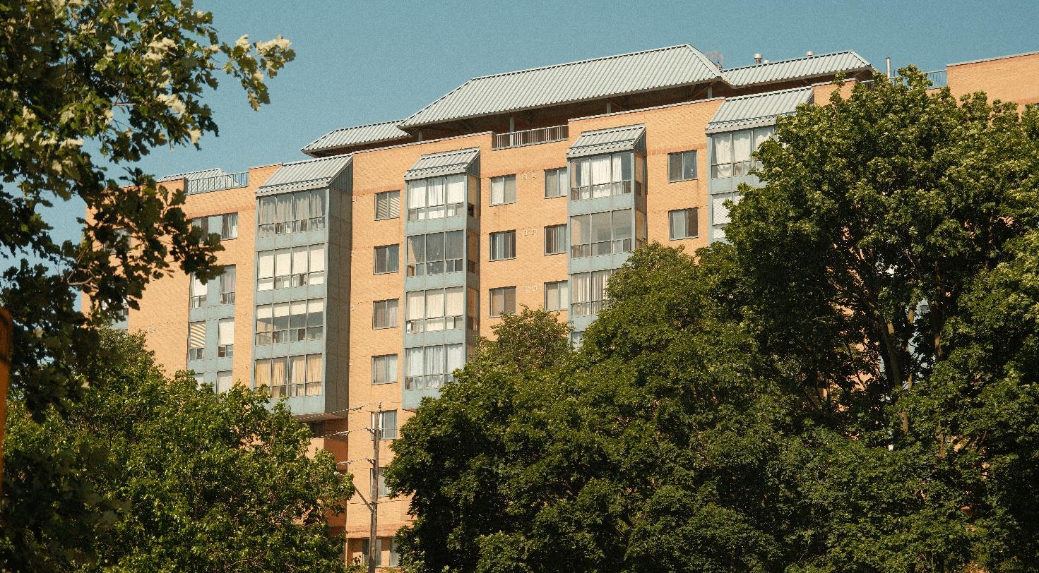 Multi-story residential building surrounded by trees, representing a senior living community.