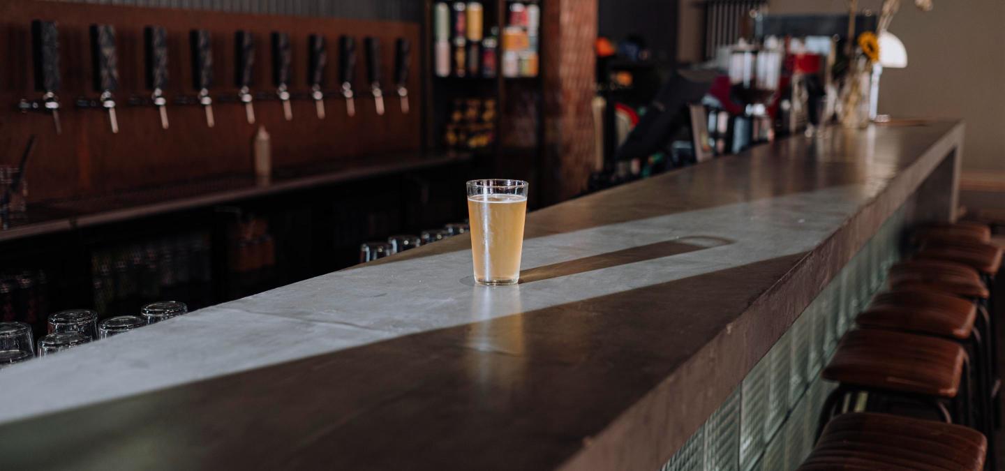 Generic craft brewery taproom bar with beer taps and a full pint glass, representing a reopened neighborhood brewery.