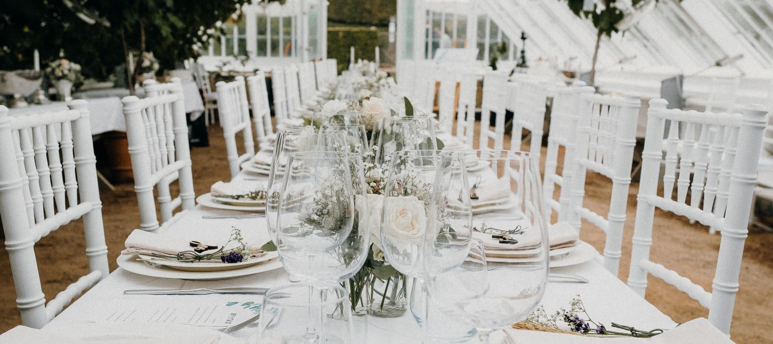 Elegant glass-roofed reception hall set for a formal dinner, representing a converted historic estate event venue.
