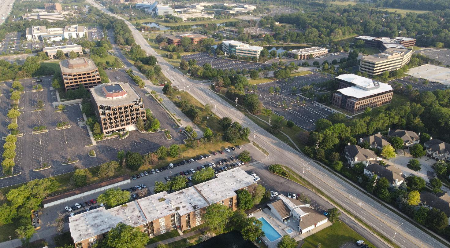 Aerial view of a suburban office park with parking lots and low-rise office buildings, representing a King of Prussia office corridor.