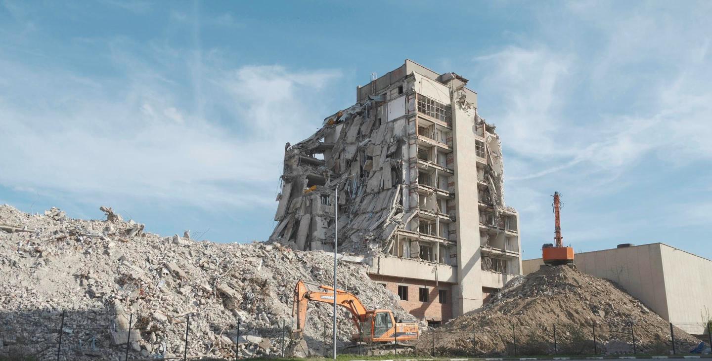 Excavators clearing rubble at a large building demolition site, representing a regional mall's partial teardown.
