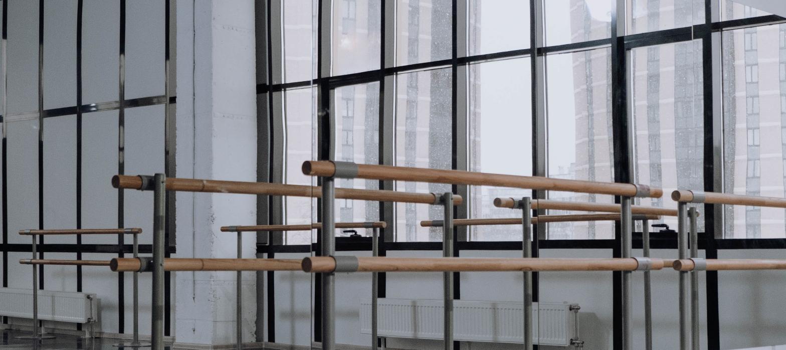 Empty modern dance studio with ballet barres and floor-to-ceiling windows, representing a new performing arts building.