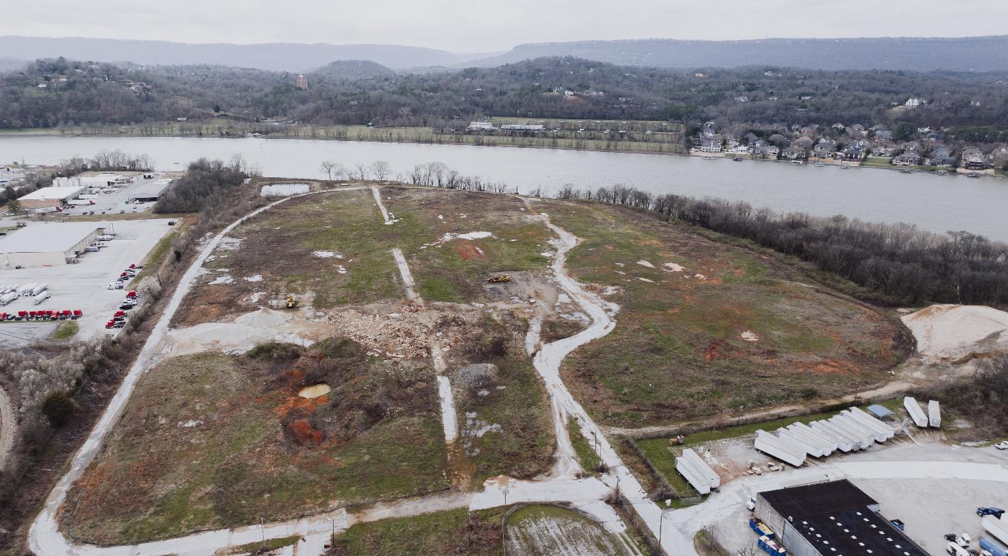 Aerial view of vacant riverside land cleared for development, representing a stalled waterfront residential project.