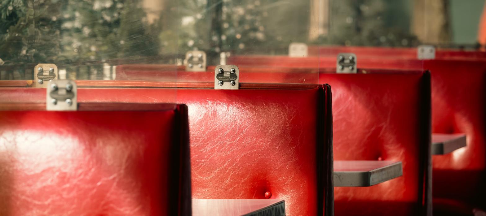 Row of red vinyl diner booths, representing a casual dining restaurant space changing operators.