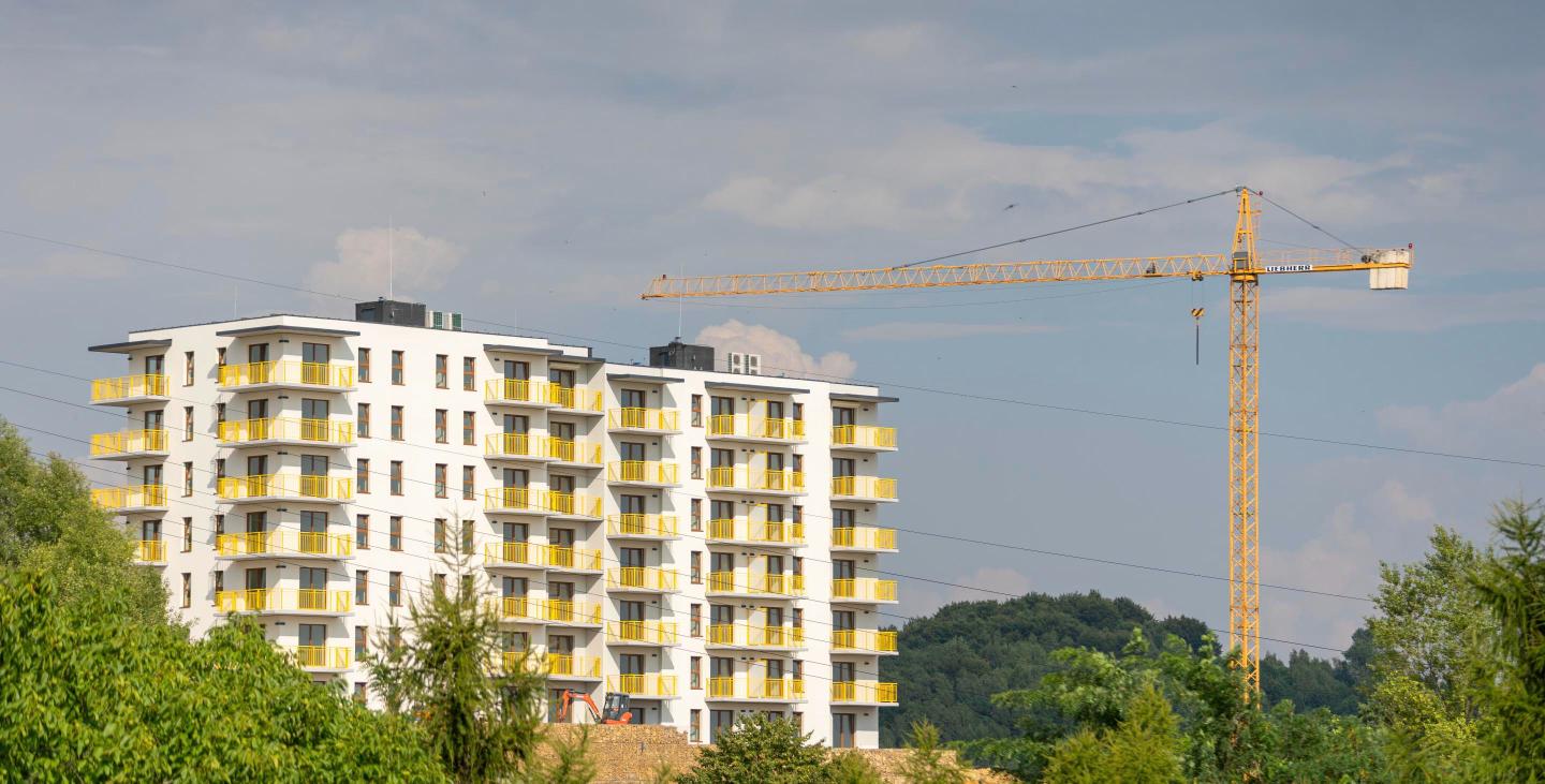 A white apartment building under construction with a tower crane overhead, representing a Port Richmond multifamily development.