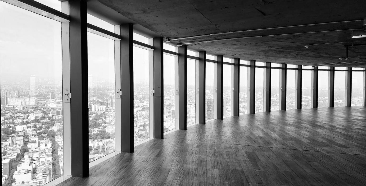 Empty raw office floor with floor-to-ceiling windows overlooking a city skyline, representing a full-floor office lease before buildout.