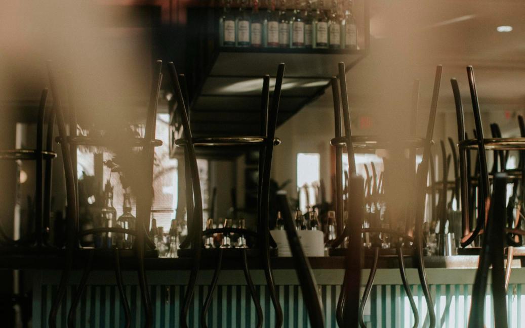Indoor view of a vintage bar with upturned chairs on the counter, representing a closed restaurant space.