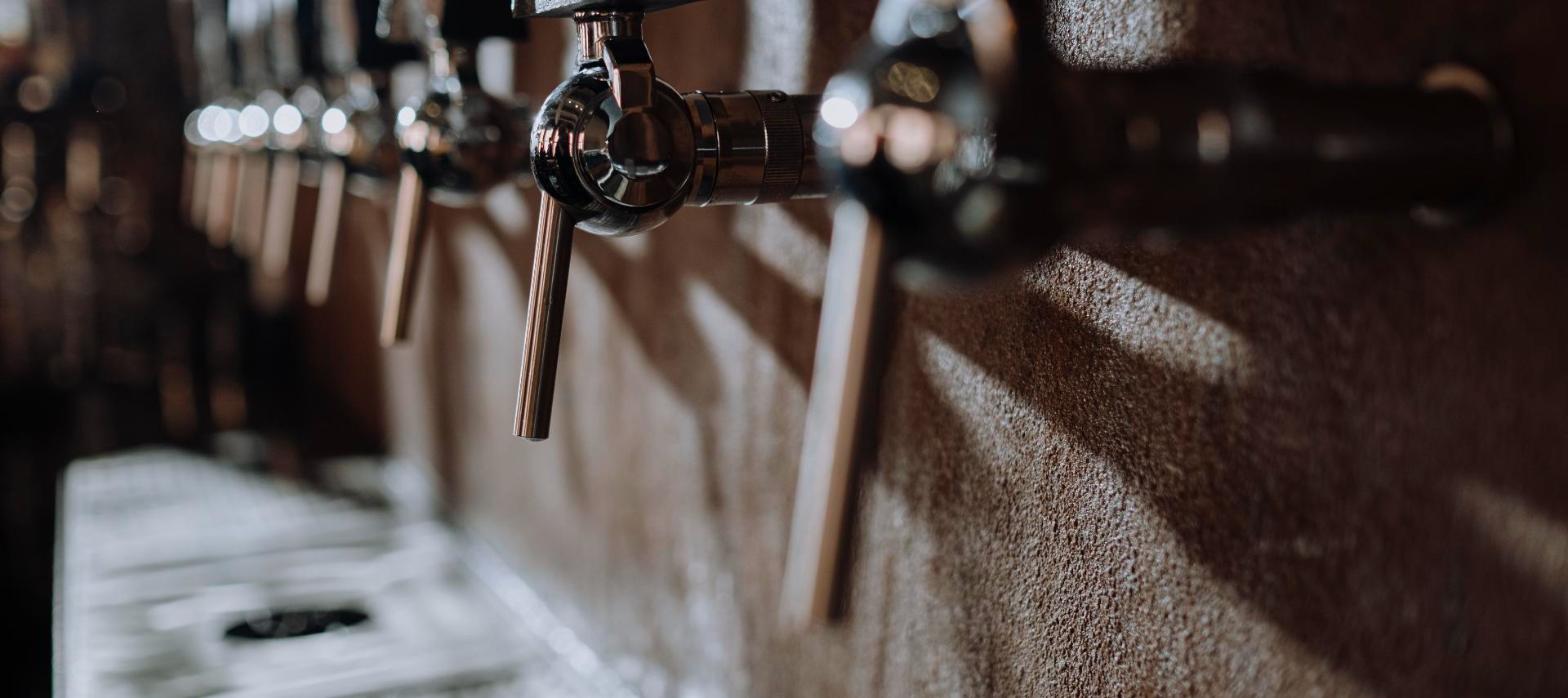 Close-up of beer taps against a textured wall, representing a brewery taproom inside a converted historic building.