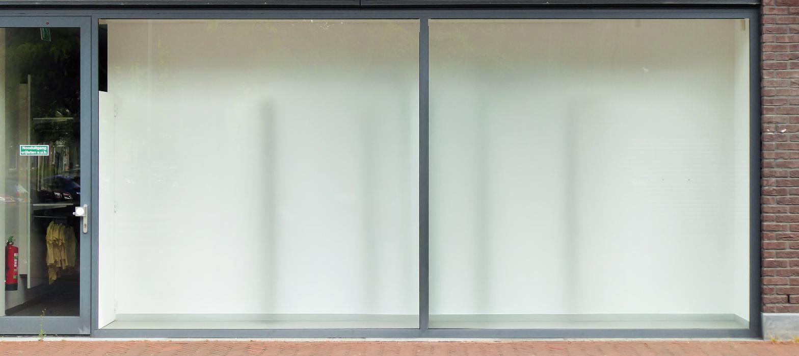 Empty retail storefront with large glass windows, representing a closed coffee shop space available for lease.