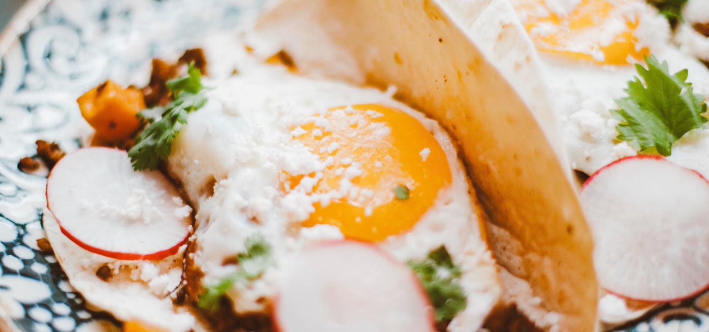 Close-up of a breakfast taco with a fried egg, cotija cheese and radish, representing a breakfast-taco concept expanding into a food hall stall.