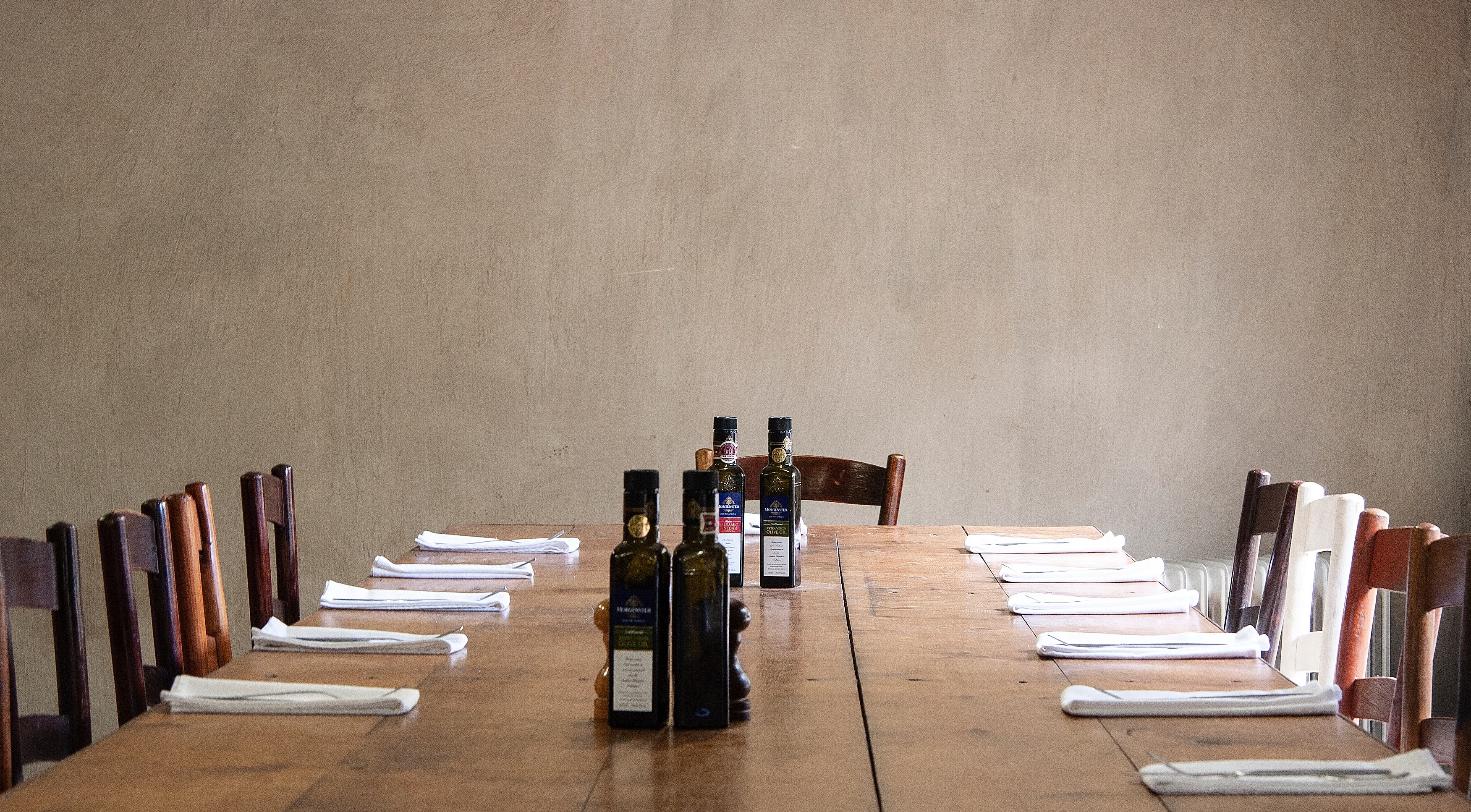 Empty restaurant dining table set with olive oil bottles and folded napkins, representing a closed Italian restaurant space.