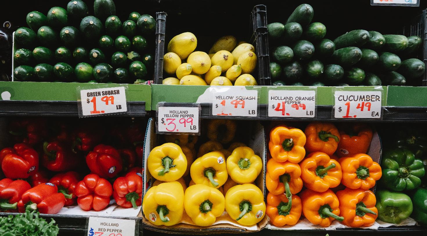 Fresh produce display with peppers and squash at a grocery store, representing a gourmet grocery market expansion.