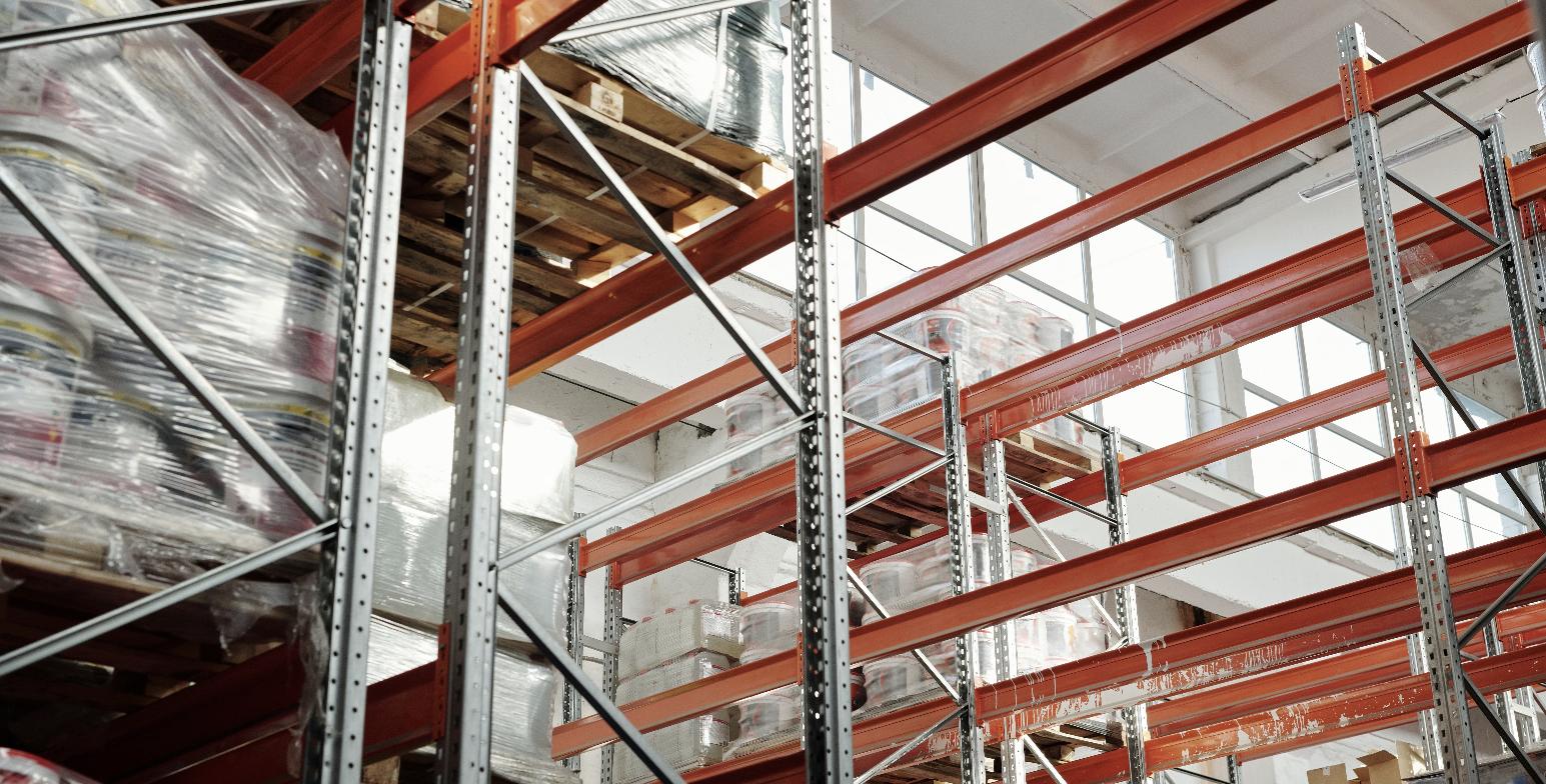 Industrial warehouse racking loaded with wrapped pallets, representing a food production and distribution facility.